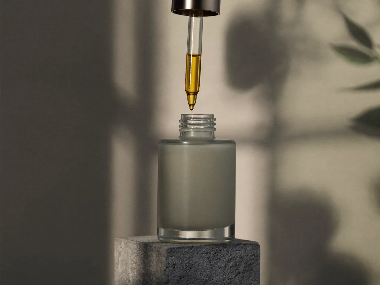 Flacon pipette en verre dépoli avec une goutte de sérum ambré sur un bloc de béton